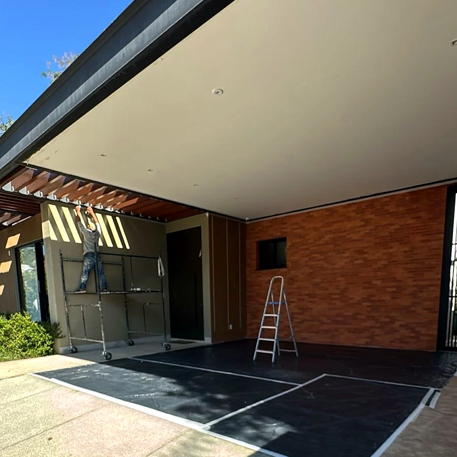 Frente de casa residencial em acabamento pela HC Engenharia, com garagem coberta, pergolado de madeira e parede em tijolinho